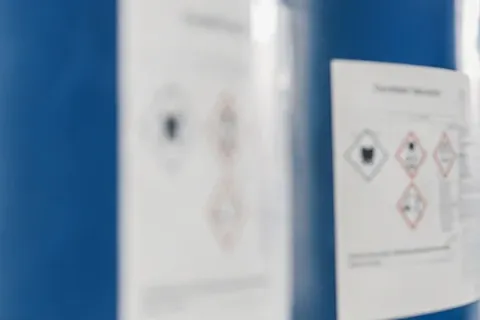 Industrial chemical drums and safety labels inside a controlled storage facility